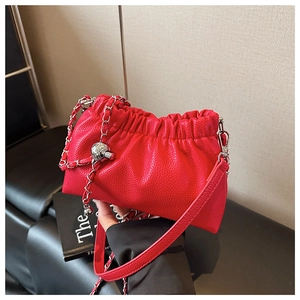 Gros plan sur le cuir rouge avec chaîne à boule argentée et détails plissés du sac