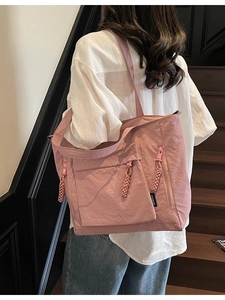 Pink nylon tote bag with multiple zipper pockets and woven pullers in a casual style