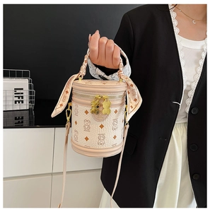 Detail of beige bear monogram bucket bag featuring silk scarf handle and gold bear zipper