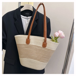 Détail du sac de plage tissé avec des poignées en cuir marron et des rayures