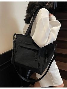 Minimalist black nylon tote bag with adjustable shoulder strap and large front pocket