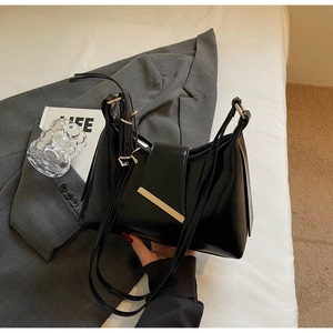 Detail der schwarzen Lackleder-Schultertasche mit Metallbesatz und verstellbaren Schnallen