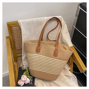 Détail du sac cabas tissé à rayures avec bandoulières en cuir marron sur une chaise