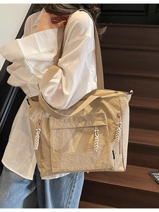 Khaki nylon tote bag with rope zipper pullers and large capacity shown on wooden stairs