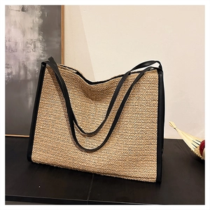 Détail de la texture d'un sac cabas en paille avec bordures et anses en cuir noir