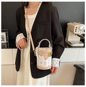 Detail of white cylinder bucket bag featuring colorful bear prints and a silk-wrapped handle
