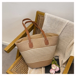 Détail d'un sac cabas en paille tissé main avec anses en cuir marron et rayures