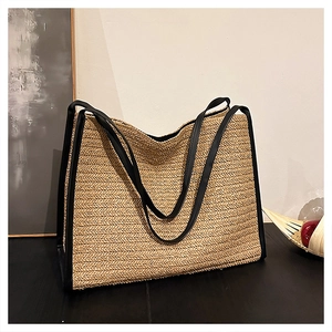 Détail du sac cabas en paille beige avec finitions en cuir noir et texture à chevrons