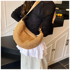Detail of woven straw hobo bag with wide shoulder strap in a lifestyle setting