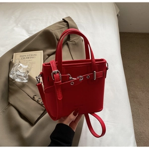 Dettaglio della borsa tote in pelle rossa con fibbie argentate e manici eleganti