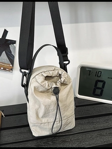 Minimalist beige nylon drawstring crossbody bag with adjustable shoulder strap and texture