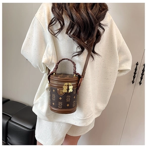 Detail of a brown vintage bucket bag featuring lucky bear patterns and woven top handle