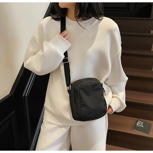 Modell mit einer minimalistischen schwarzen Nylon-Umhängetasche für Handys
