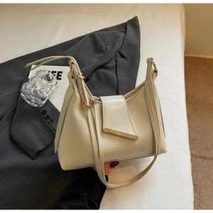 Nahaufnahme einer minimalistischen cremefarbenen Ledertasche mit elegantem Goldmetallstab