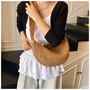 Detail of the woven texture and fabric strap on this beige straw crescent crossbody bag