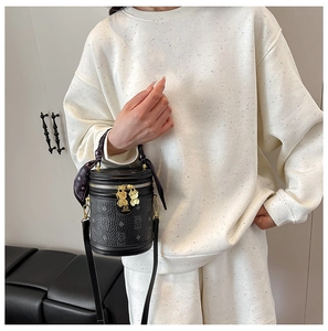 Detail of black cylindrical bucket bag with bear zipper and decorative silk scarf