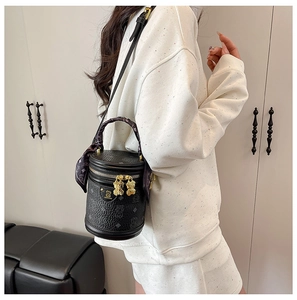 Detail of black cylinder bucket bag with bear logo and scarf wrapped around handle