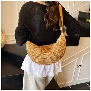 Detail of hand-woven straw crossbody bag with wide strap on a model for daily use
