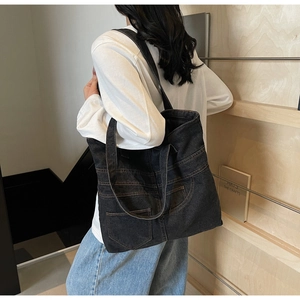 Detailed view of large black denim tote bag featuring decorative stitching and sturdy seams
