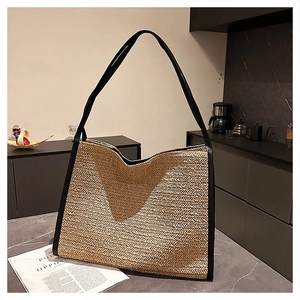 Détail du grand sac cabas en paille avec bordure en cuir noir et texture tressée