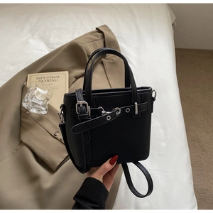 Dettaglio borsa a secchiello in pelle litchi nera con trama granulata e fibbie decorative