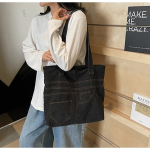Detail of black denim tote bag with brown contrast stitching and decorative pocket