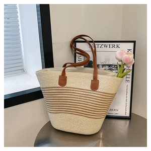 Gros plan d'un sac cabas tissé beige avec rayures marron et anses en similicuir