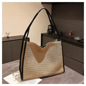 Détail du tissage en paille en V et des finitions en cuir noir sur un grand sac cabas