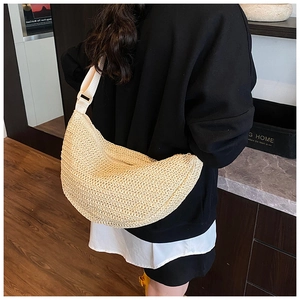 Detail of cream woven half-moon crossbody bag shown worn on a model's back in a home setting