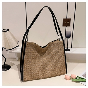 Détail d'un sac cabas en paille tressée avec bordure en similicuir noir et doubles anses