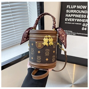 Detail of cylinder bag with bear pattern, golden bear-shaped zippers, and silk scarf wrap