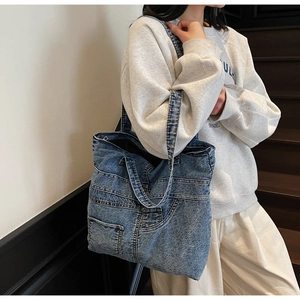 Detail view of large blue washed denim tote bag with multi-pocket design on stairs