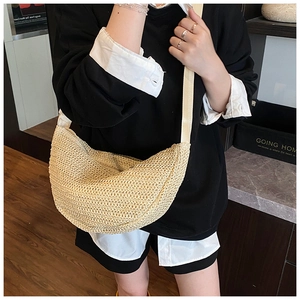 Detailed texture of the beige woven crescent bag with wide fabric shoulder strap