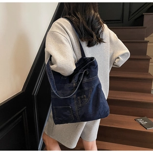 Detailed view of blue denim tote bag featuring vintage stitching and side pockets