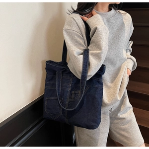 Detail view of vintage blue denim tote bag showing decorative pockets and contrast stitching