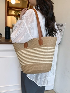Grand sac cabas en paille à rayures avec anses en cuir marron porté par un mannequin
