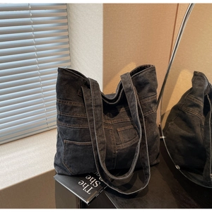 Detail of dark denim tote bag with vintage brown stitching and jean pocket design