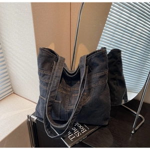 Detail of vintage blue denim tote bag with functional pockets and contrast stitching