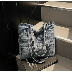 Detail of vintage blue patchwork denim tote bag with functional pockets on black book