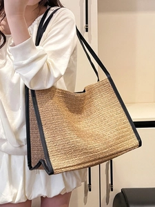 Sac fourre-tout minimaliste en paille avec garniture en cuir noir porté par un mannequin