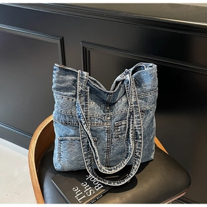 Detail of vintage washed denim tote bag with functional pockets and white contrast stitching