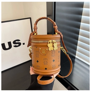 Detailed view of brown cylinder bucket bag featuring bear patterns and silk scarf handle