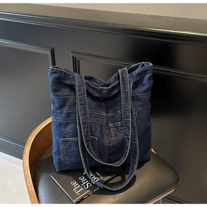 Detailed close-up of blue denim tote bag with vintage pocket and orange double stitching