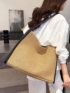 Sac fourre-tout minimaliste en paille avec bordure en similicuir noir porté par mannequin