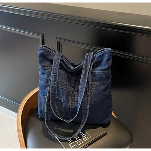 Close-up of deep blue denim tote bag with deconstructed pockets and stitching details