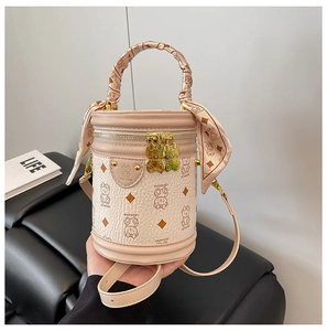 Detail of a pink bucket bag with bear patterns and a silk scarf wrapped on the handle