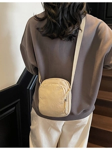 Minimalistische beige Nylon-Umhängetasche für Handys am Modell mit Gurt
