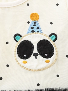 Détail d'une robe en coton à pois noirs avec broderie panda et chapeau bleu