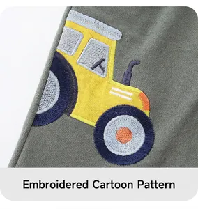 Detail of yellow tractor embroidery on olive green cotton shorts for boys
