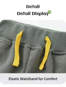 Detail of elastic ribbed waistband and yellow drawstring on olive green boy's shorts